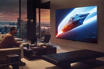 Stilfuld stue in en penthouselejlighed. Smuk udsigt til by gennem vinduet. En mand sidder på sofaen og ser indhold på et vægmonteret tv.