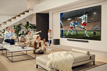 En familie er samlet omkring deres Ultrastore LG-tv, hvorpå de ser en spændende fodboldkamp.