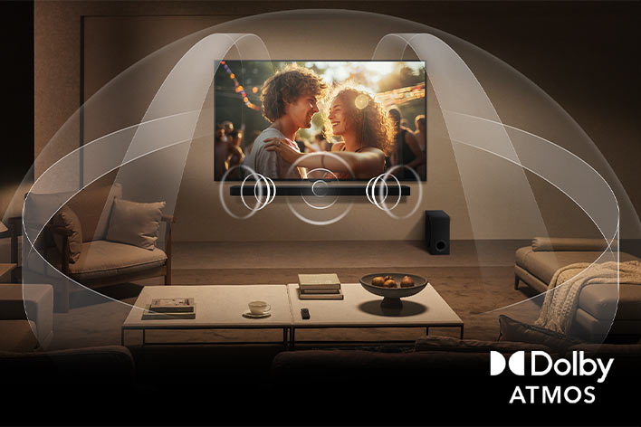 Hyggelig stue med dæmpet belysning og et LG QNED TV på en væg med en LG Soundbar. Grafik viser, hvordan Dolby Atmos fylder hele rummet med surroundlyd fra alle retninger. Dolby Atmos-logoet ses i nederste højre hjørne.