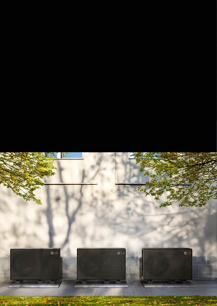 Et sort LG THERMA V-produkt er anbragt i haven omkring et hus, og en kvinde med en kasse går forbi foran det.