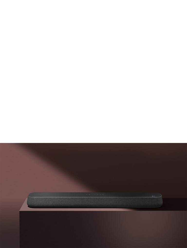 LG Soundbar SE6S står på den røde æske foran en rød baggrund. En sort skygge dækker den øverste højre halvdel af billedet.