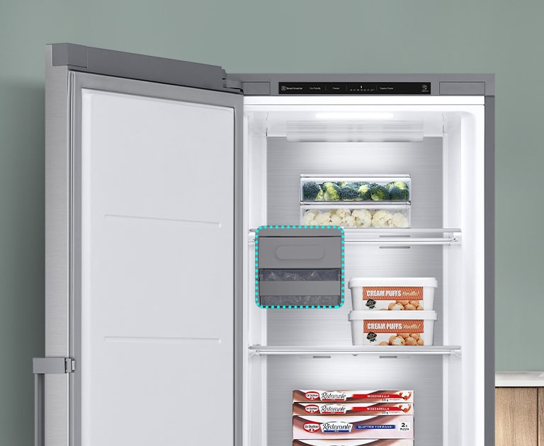 Fryseren er åben, og varerne ligger på forskellige hylder. En blå stiplet linje fremhæver, hvor ismaskinen kunne være, men viser, at den kan fjernes for at give ekstra plads.