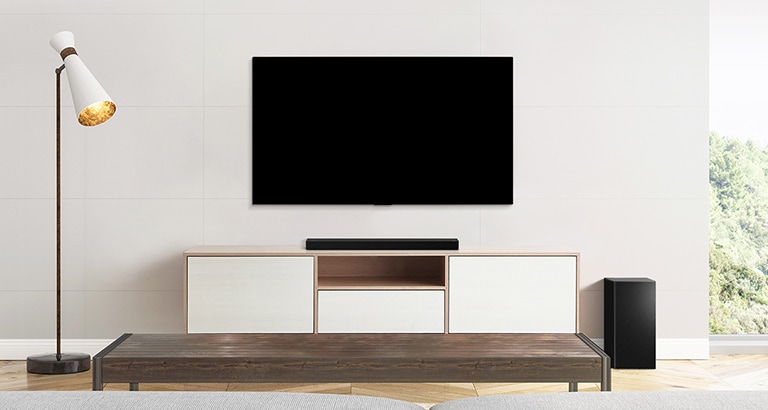 Et tv, en soundbar og en subwoofer placeret i en almindelig stue.