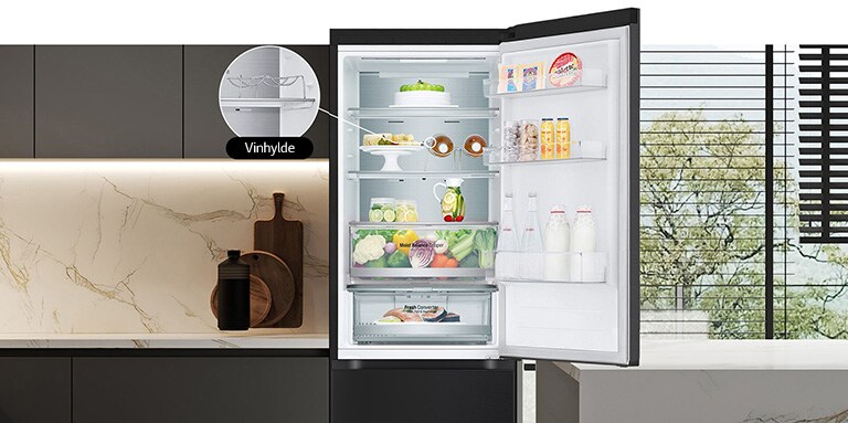 Køleskab med åben dør fyldt med frisk mad, hvor ses vinhylde og foldehylde.