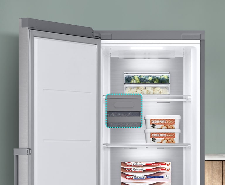 Fryseren er åben, og varerne ligger på forskellige hylder. En blå stiplet linje fremhæver, hvor ismaskinen kunne være, men viser, at den kan fjernes for at give ekstra plads.