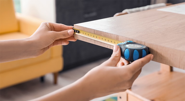 Someone is measuring the size of the furniture using a tape measure.