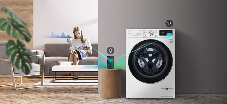 En kvinde der sidder i sofaen og drikker te og fortæller hvad vaskemaskinen skal gøre gennem sin AI-højttaler.