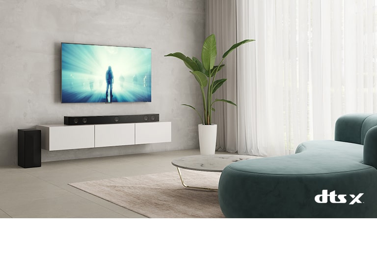 In the living room, LG TV is on the wall. A moive is playing on TV screen. LG Sound bar is right below TV on a beige shelf with a rear speaker is placed on left. Dolby Atmos Virtual logo shown on right bottom of image.