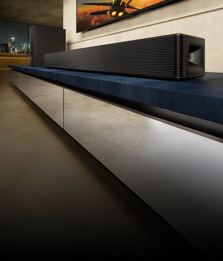 LG Soundbar SH5A and its sub woofer stand on a blue TV cabinet in a livingroom. TV with aircraft image is partially shown above the soundbar.