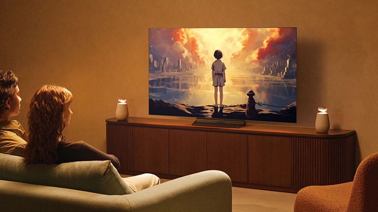 Una pareja sentada en el sofá viendo la televisión con conexión Bluetooth TV mediante el uso de LG XBOOM 360 XO2T.