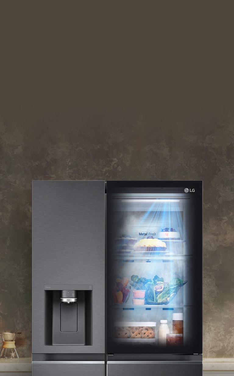 Refrigerador LG con puerta de vidrio, interior iluminado, en cocina moderna con cafetera a la izquierda.