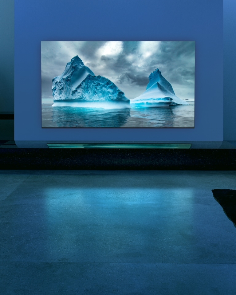Imagen de un TV QNED MiniLED de LG en un salón con tonos azules, y en la pantalla del televisor se muestra la imagen de un glaciar, también en color azul.
