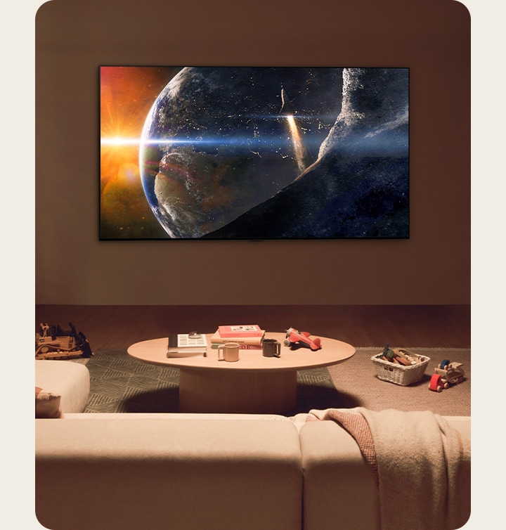 Una familia sentada en el suelo de una sala de estar con poca luz junto a una pequeña mesa, mirando un televisor LG montado en la pared que mostraba la Tierra desde el espacio.