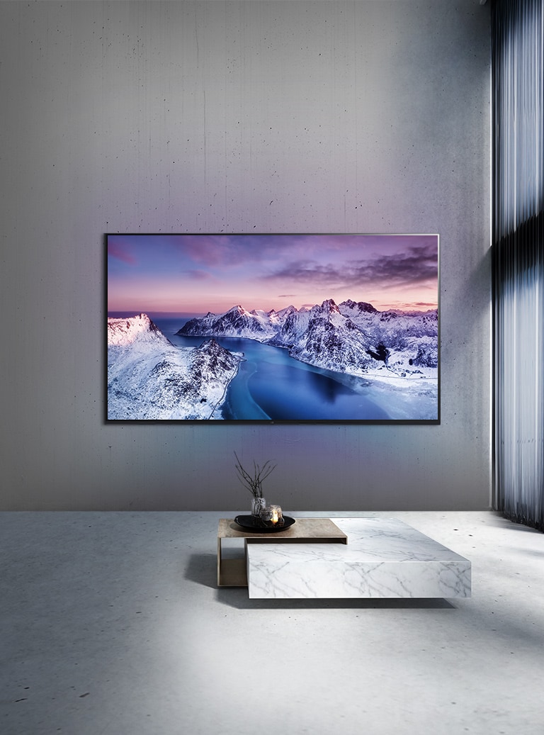 Un televisor UHD montado en la pared detrás de un tabe con ambientación de estilo zen.