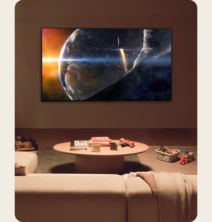 Una familia sentada en el suelo de una sala de estar con poca luz junto a una pequeña mesa, mirando un televisor LG montado en la pared que mostraba la Tierra desde el espacio.uhd-98ut90-20-home-cinema-experience-d.jpg