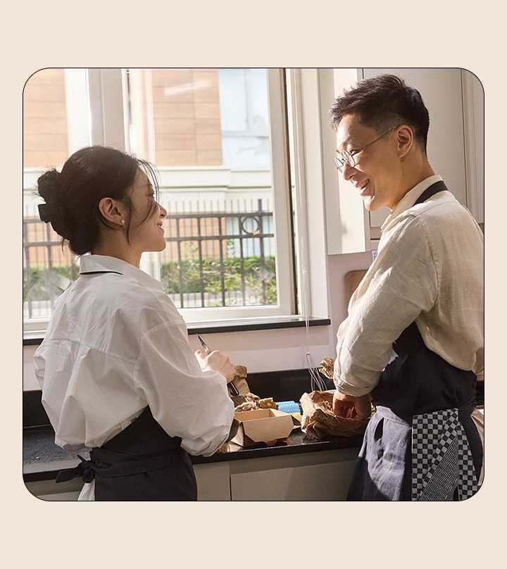 Un hombre y una mujer se miran mientras cocinan en la cocina.