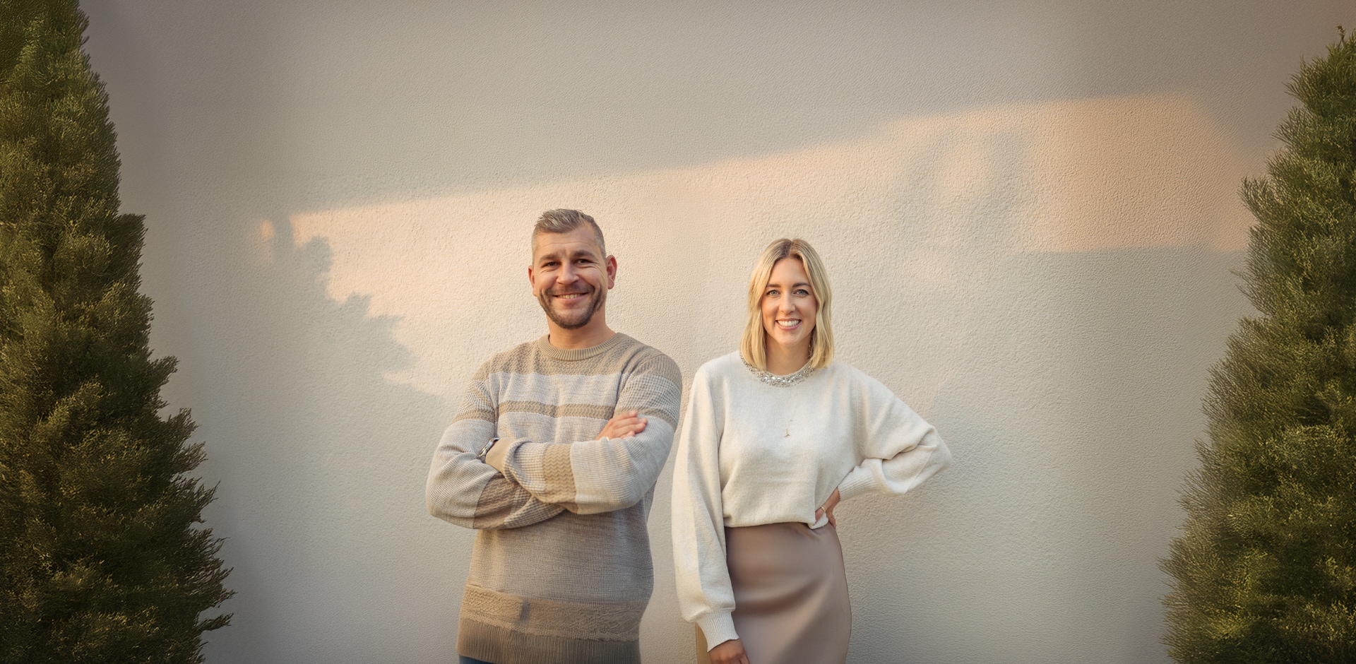 Una pareja sonríe entre dos árboles de Navidad.