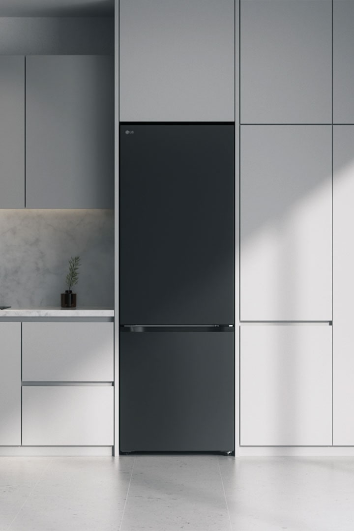 El congelador inferior LG negro mate está empotrado en armarios grises, junto a una encimera de mármol con placa de inducción y una gran ventana a la derecha.