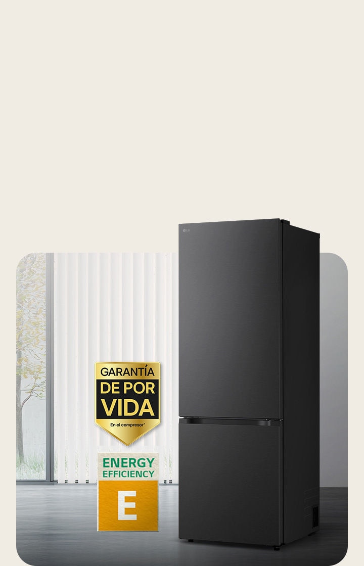 Vista frontal de un congelador inferior LG negro mate, colocado en una habitación luminosa con persianas verticales. A continuación se muestran la garantía de 10 años del compresor y los iconos de eficiencia energética A.