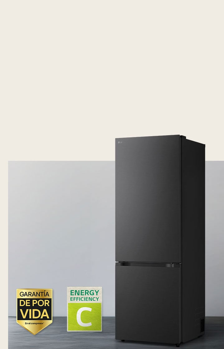 Vista frontal de un congelador inferior LG negro mate, colocado en una habitación luminosa con persianas verticales. A continuación se muestran la garantía de 10 años del compresor y los iconos de eficiencia energética A.