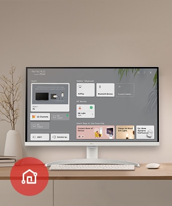 En la mesa el monitor muestra la pantalla del home dashboard con el icono de la app LG ThinQ visible en la esquina inferior izquierda.