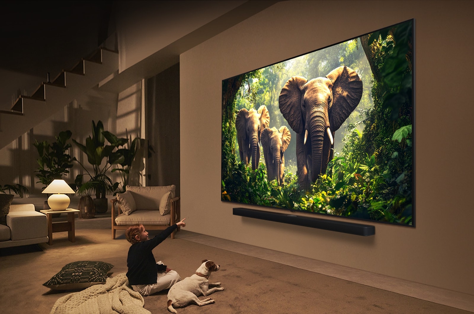 Une fille et un chien sont assis devant une LG QNED TV installée sur un mur représentant trois éléphants marchant vers l’extérieur au-dessus d’une LG Soundbar. Le titre évoque la façon dont chaque scène d’action est plus palpitante sur un très grand écran.