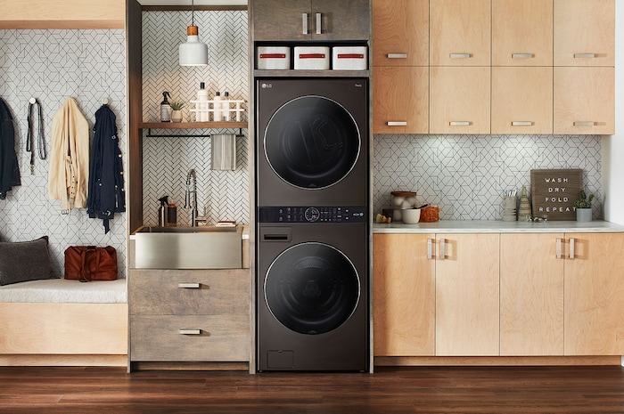 La LG WashTower® F761TOWERB2 en acier noir, installée dans une buanderie moderne avec des armoires en bois.