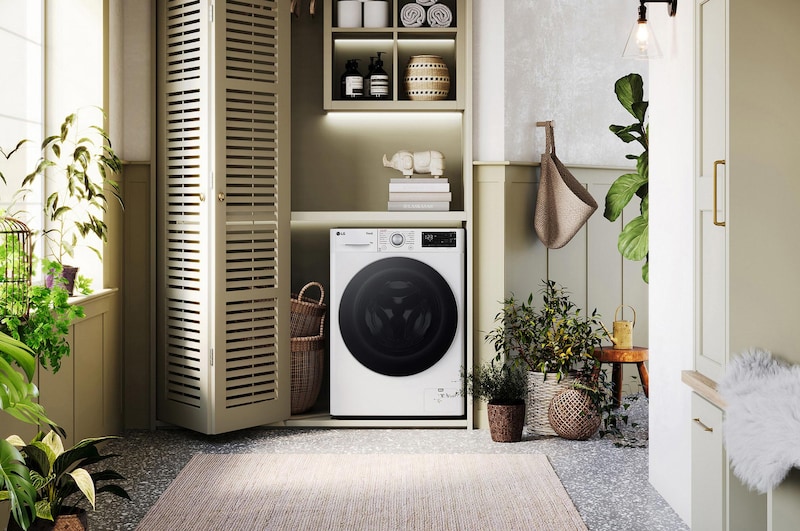 Lave-linge LG F94R31WHSA blanc installé dans une buanderie confortable avec des placards à persiennes et des plantes vertes.