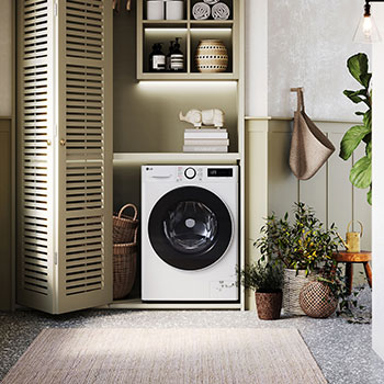 Lave-linge LG F92SR50WHS blanc installé dans une buanderie confortable avec des placards à persiennes et des plantes vertes.