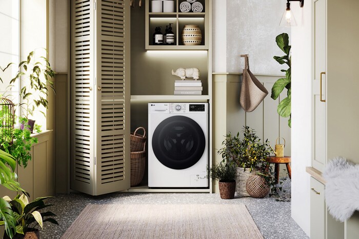 Lave-linge LG F14R31WHSA blanc installé dans une buanderie confortable avec des placards à persiennes et des plantes vertes.