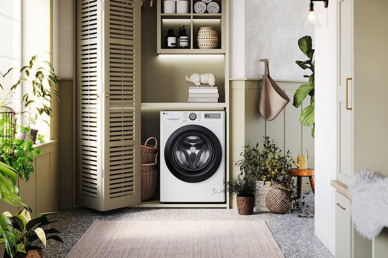 Lave-linge LG F14R15WHS blanc installé dans une buanderie confortable avec des placards à persiennes et des plantes vertes.