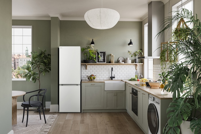 Réfrigérateur-congélateur LG GBV3100ESW blanc, intégré dans une cuisine moderne aux tons verts, mettant en valeur son design élégant à porte plate.