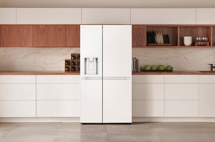 Réfrigérateur Américain LG GSLC40SWPE Blanc avec distributeur d'eau et de glace, intégré élégamment dans une cuisine moderne et lumineuse aux armoires blanches et en bois.
