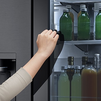 La vue avant du réfrigérateur à verre noir InstaView avec de la lumière à l’intérieur Des mains appuient sur l’écran InstaView.
