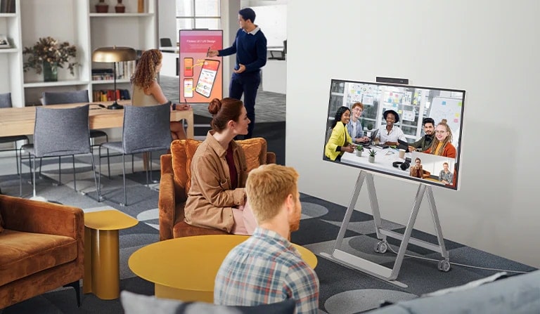 Deux personnes sont en visioconférence à l’aide du One:Quick Flex dans un espace professionnel. Deux autres personnes sur une table derrière eux ont une conférence en inclinant le One:Quick Flex verticalement. Ils prennent des notes et écrivent directement dessus en utilisant un stylet tactile dédié.