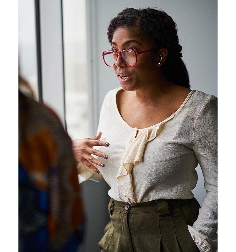 Deux femmes sont en train de discuter. La femme que nous voyons de face porte les écouteurs.