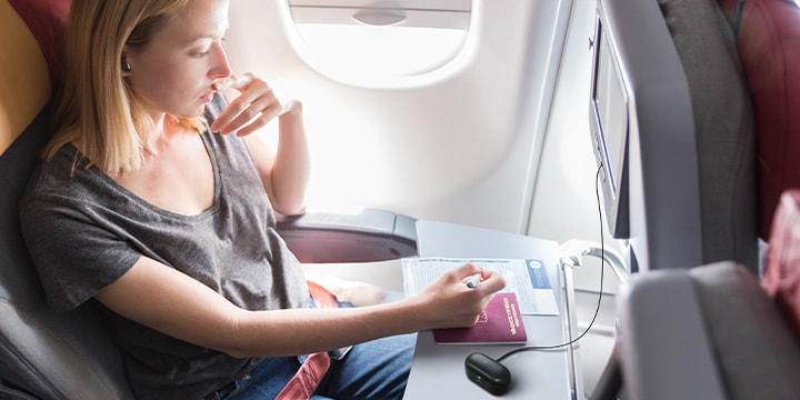 Une femme portant des T90S pour profiter du divertissement à bord d’un avion en utilisant la fonction Plug & Wireless.