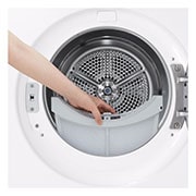 Main retirant le filtre à charpie d’un sèche-linge frontal pour l’entretien régulier.