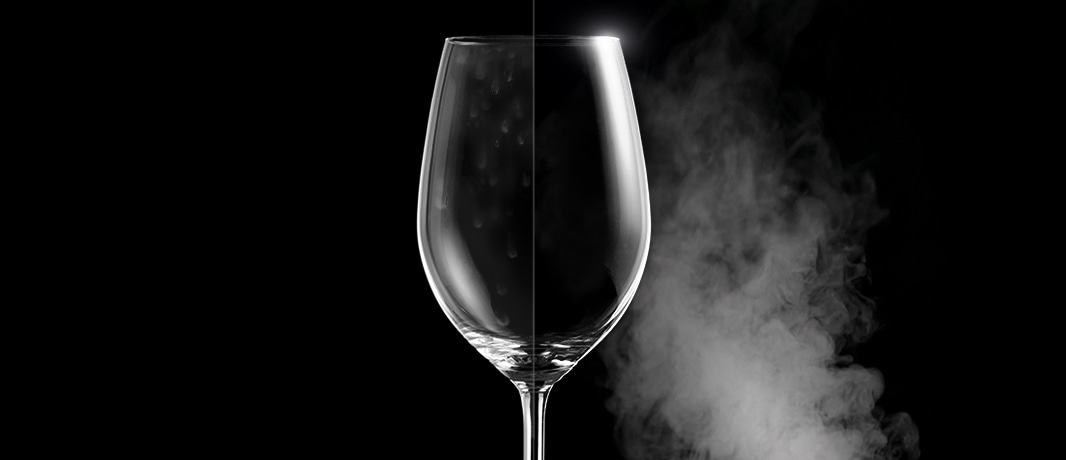 Un verre de vin avec des taches d'eau d'un côté, et clair et immaculé de l'autre après un lavage à la vapeur.