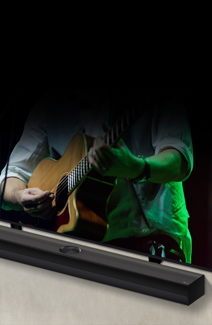 La LG Soundbar sur un arrière-plan noir révèle son design en commençant par l’angle gauche, avant de montrer la barre de son dans son ensemble. Une LG QNED TV apparaît avec le Synergy Bracket. La Soundbar est posée sur le Synergy Bracket, plaquée contre le mur, la partie inférieure de l’écran de TV est visible, affichant un homme jouant de la guitare.