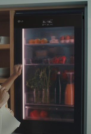 Image d’une femme frappant sur le dessus d’un réfrigérateur.