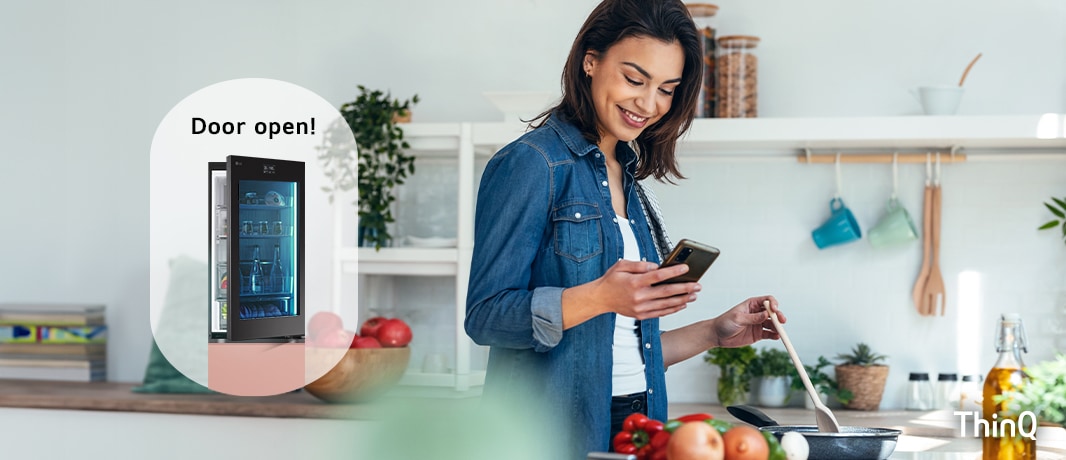 Une image d’une femme qui cuisine tout en regardant son téléphone et un réfrigérateur avec une porte ouverte.