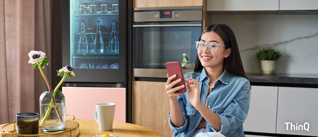 Une image d’une femme manipulant son téléphone dans la cuisine.