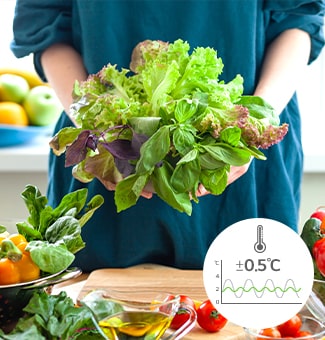 Person holding a bouquet of fresh leafy greens, surrounded by vibrant produce and a temperature gauge showing ±0.5°C.