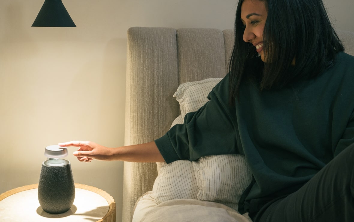 Lisa Mistry est allongée dans son lit, touchant le pavé tactile du LG Xboom XO2T avec Mood Lighting activé.