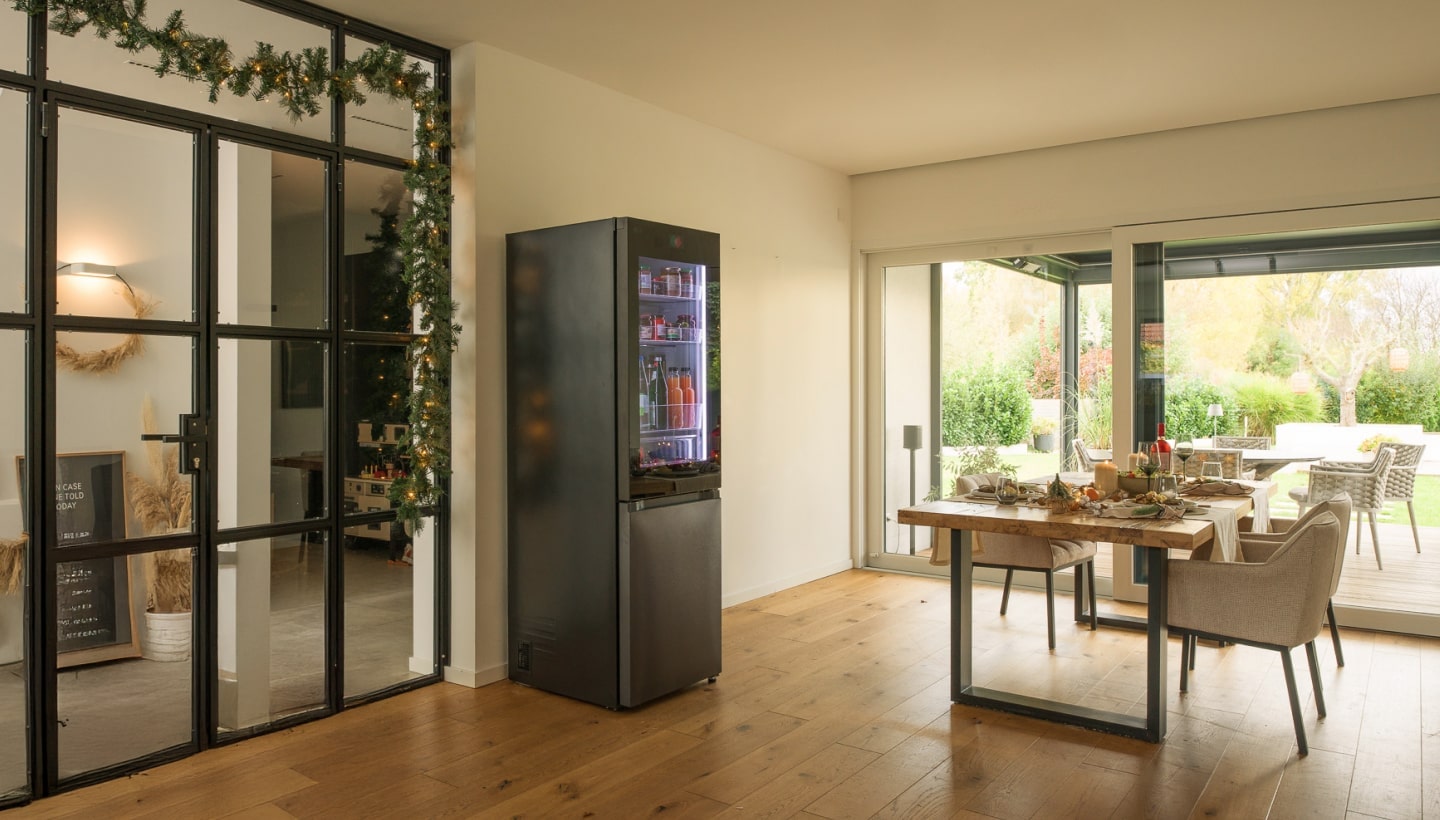 Salle à manger moderne avec un LG InstaView, une table festive et une vue sur un jardin.