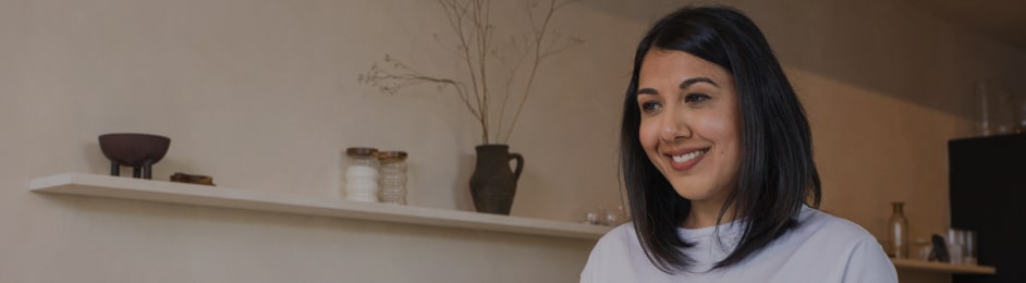 Une femme versant du thé dans une théière dans une cuisine moderne, souriante et détendue.