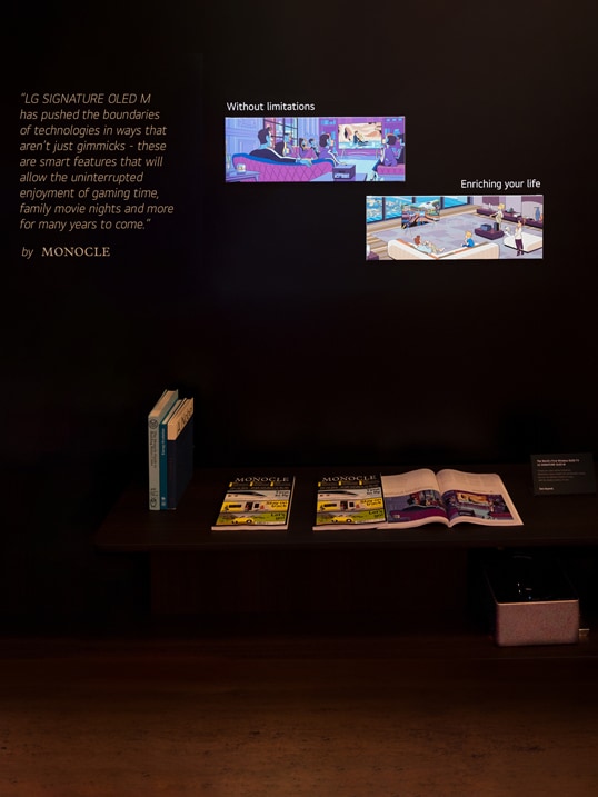 Illustrations from the OLED M editorial article from Monocle is on display, and physical copies of the magazine are placed on a table beneath.