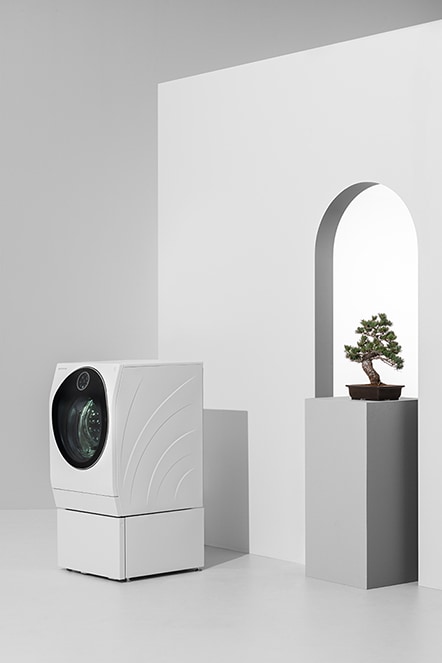 lg signature washing machine is laid in front of the white arch wall with a japanese plant pot next to it