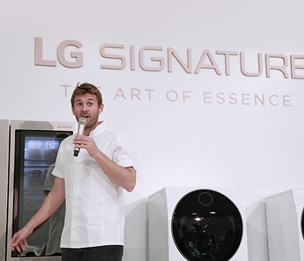 a chef influencer is talking on the main stage while pointing at lg signature refrigerator at lg signature launching event in nordics